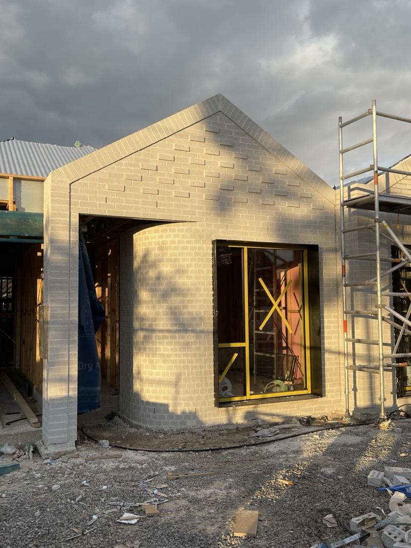 Brick gable front with a curved face-brick entry wall on a new build