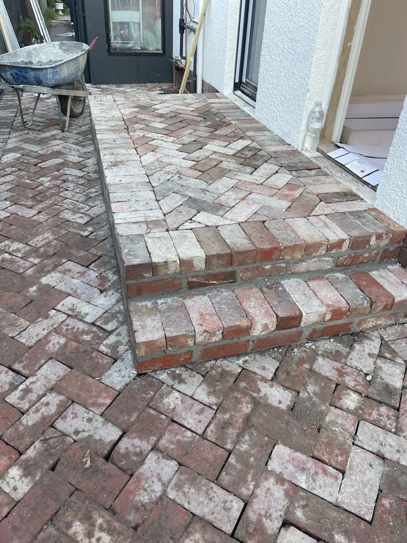 Two-step brick landing with recycled red bricks laid in herringbone