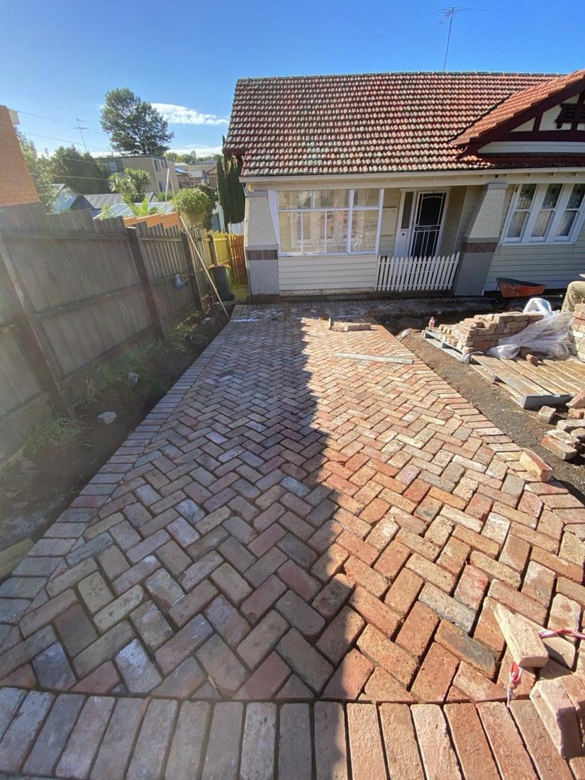 Recycled red brick driveway in herringbone with a soldier-course border in front of a bungalow
