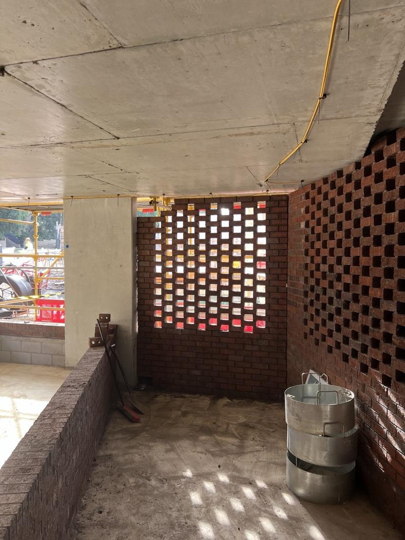 Hit-and-miss face brick screen walls in a ground-floor courtyard, with light coming through the openings