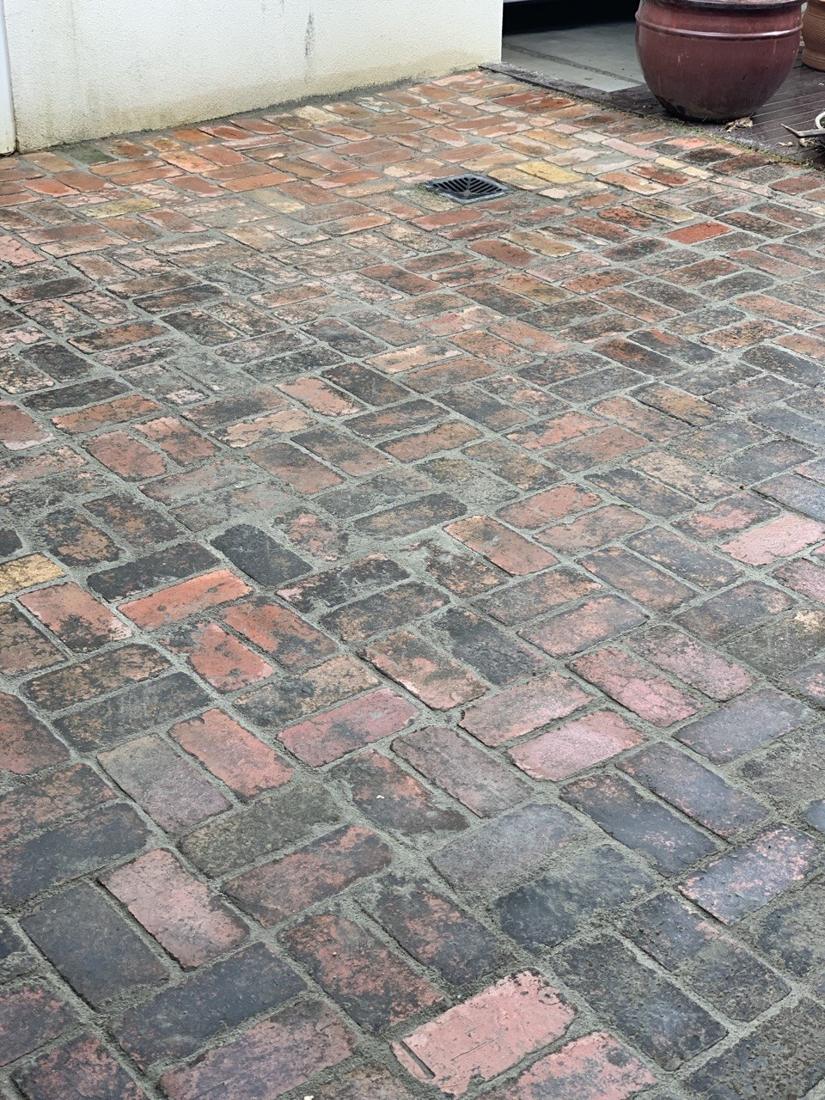 Reclaimed brick courtyard paving in herringbone with a drain grate