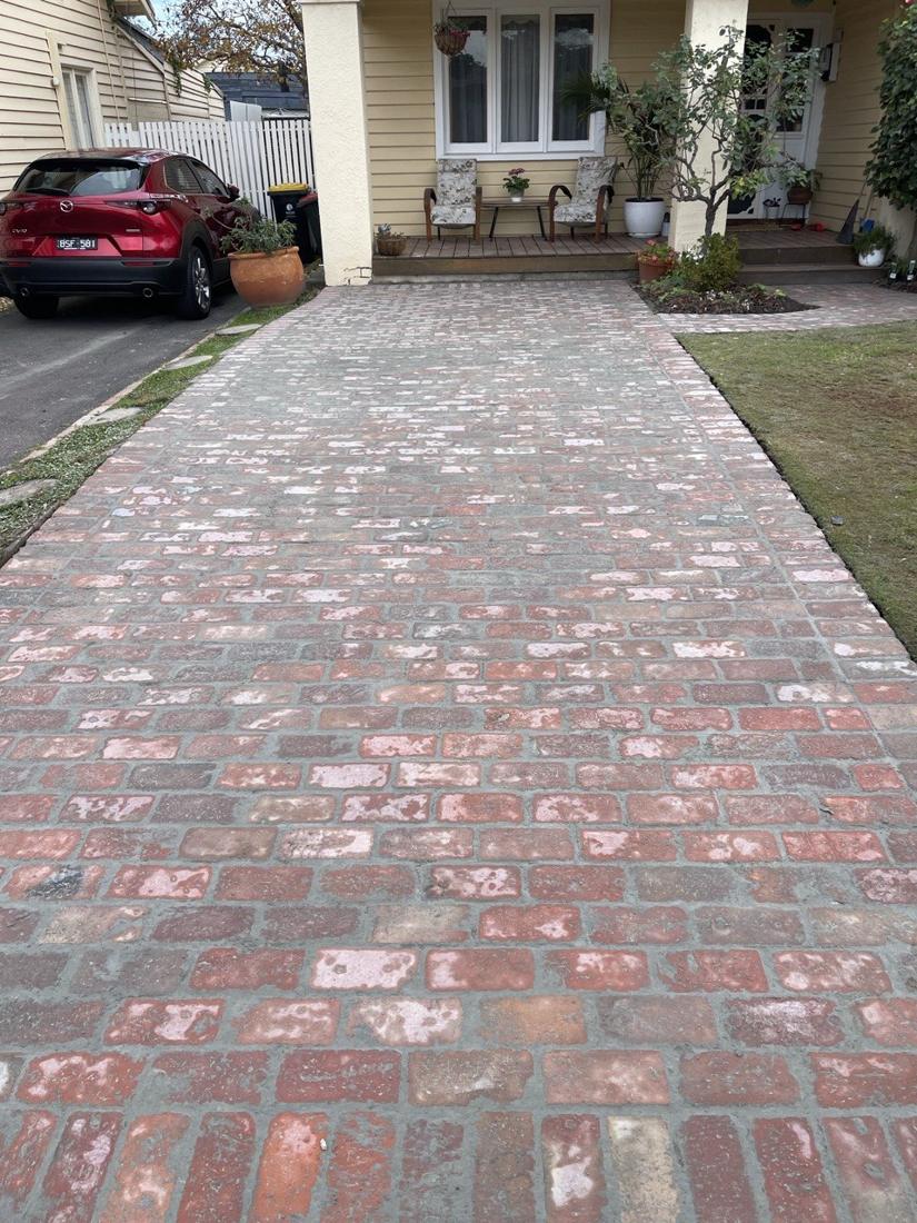 Reclaimed red brick driveway laid in stretcher bond up to a weatherboard veranda