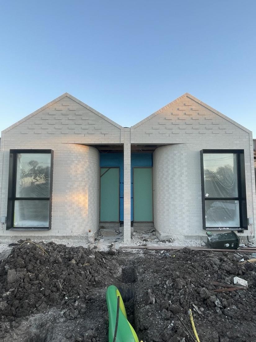 Twin-gable dual occupancy new build in light face brick with curved brick entry walls